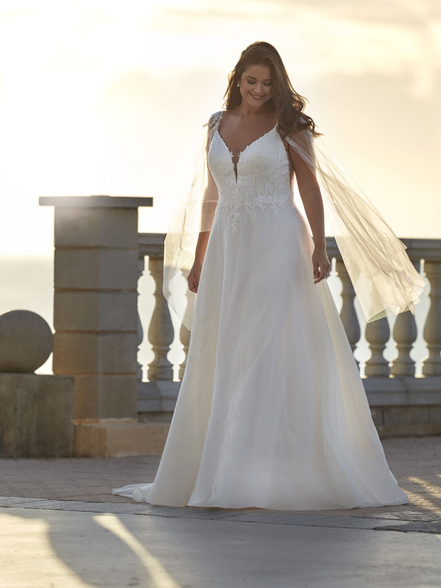 Eine Frau in einem weißen Brautkleid und Schleier steht auf einem Balkon.