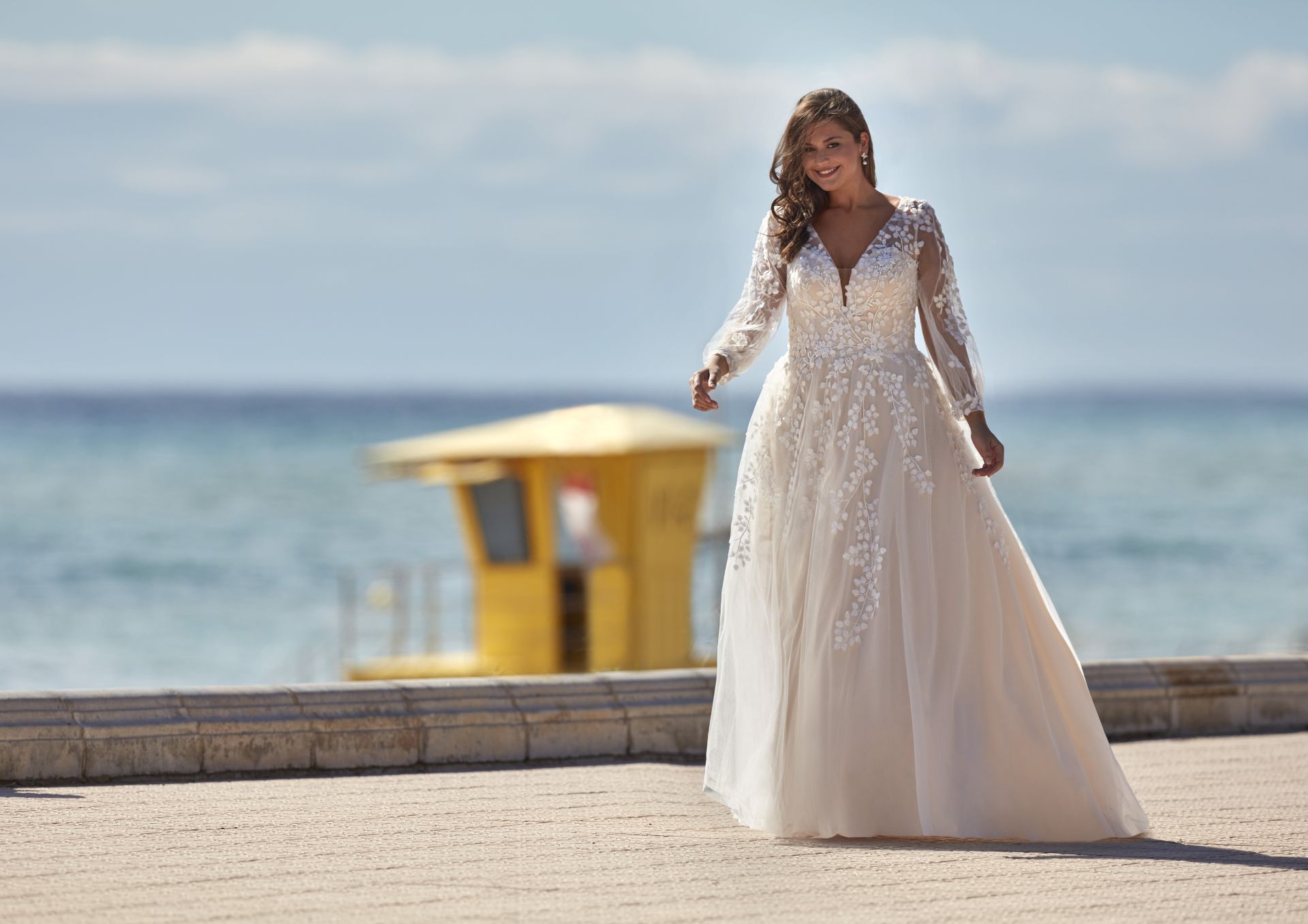 Eine Frau in einem Brautkleid steht an einem Strand.