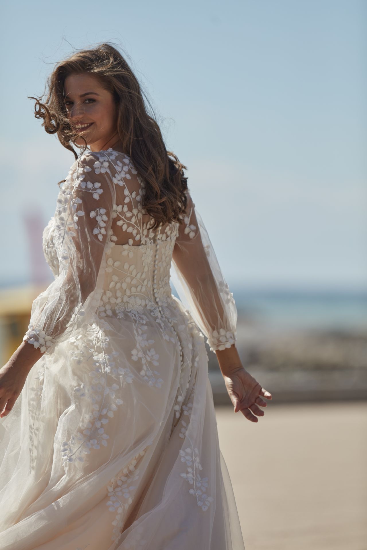 Eine Frau in einem Brautkleid geht am Strand spazieren.