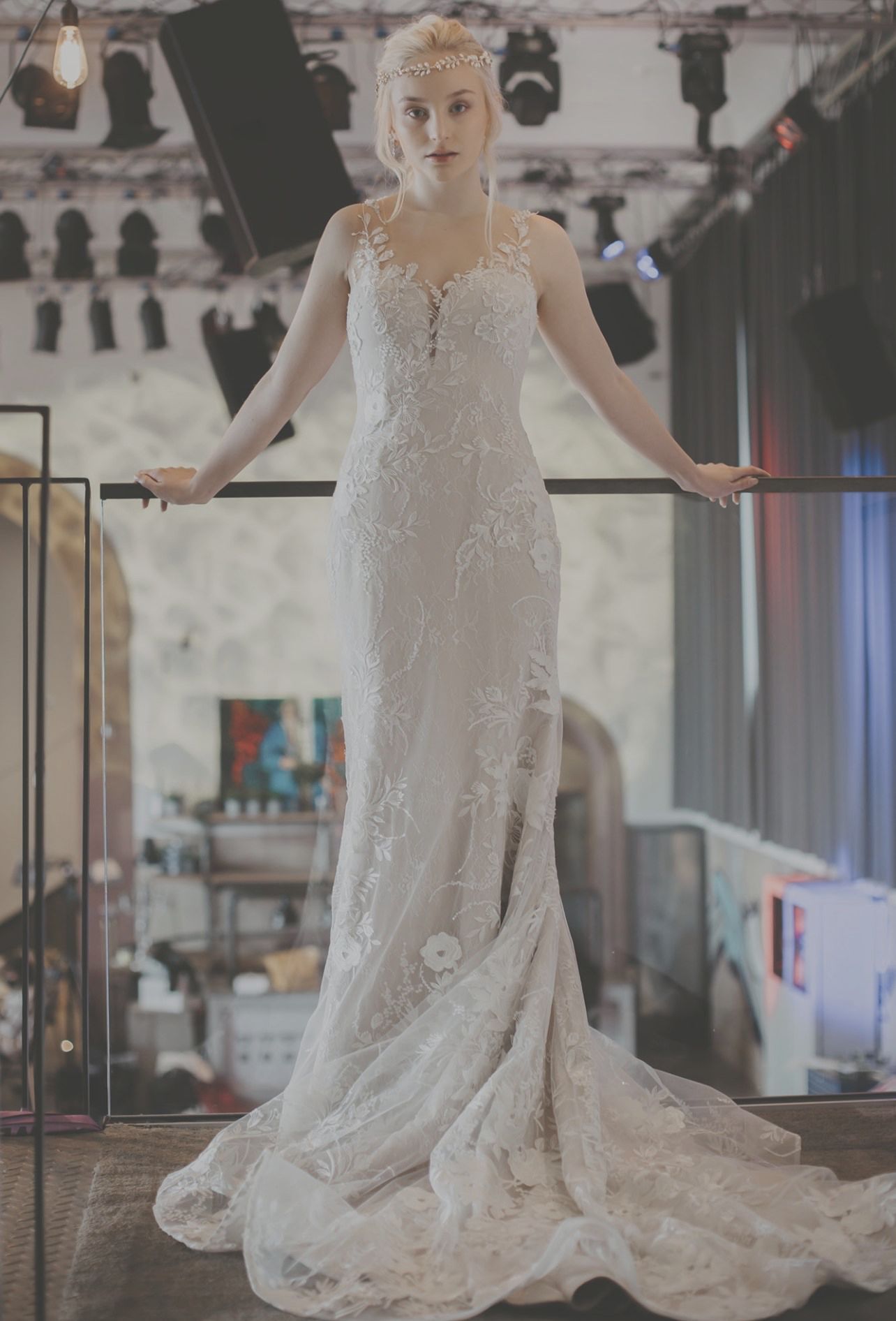 Eine Frau in einem Brautkleid steht mit ausgestreckten Armen in einem Raum.