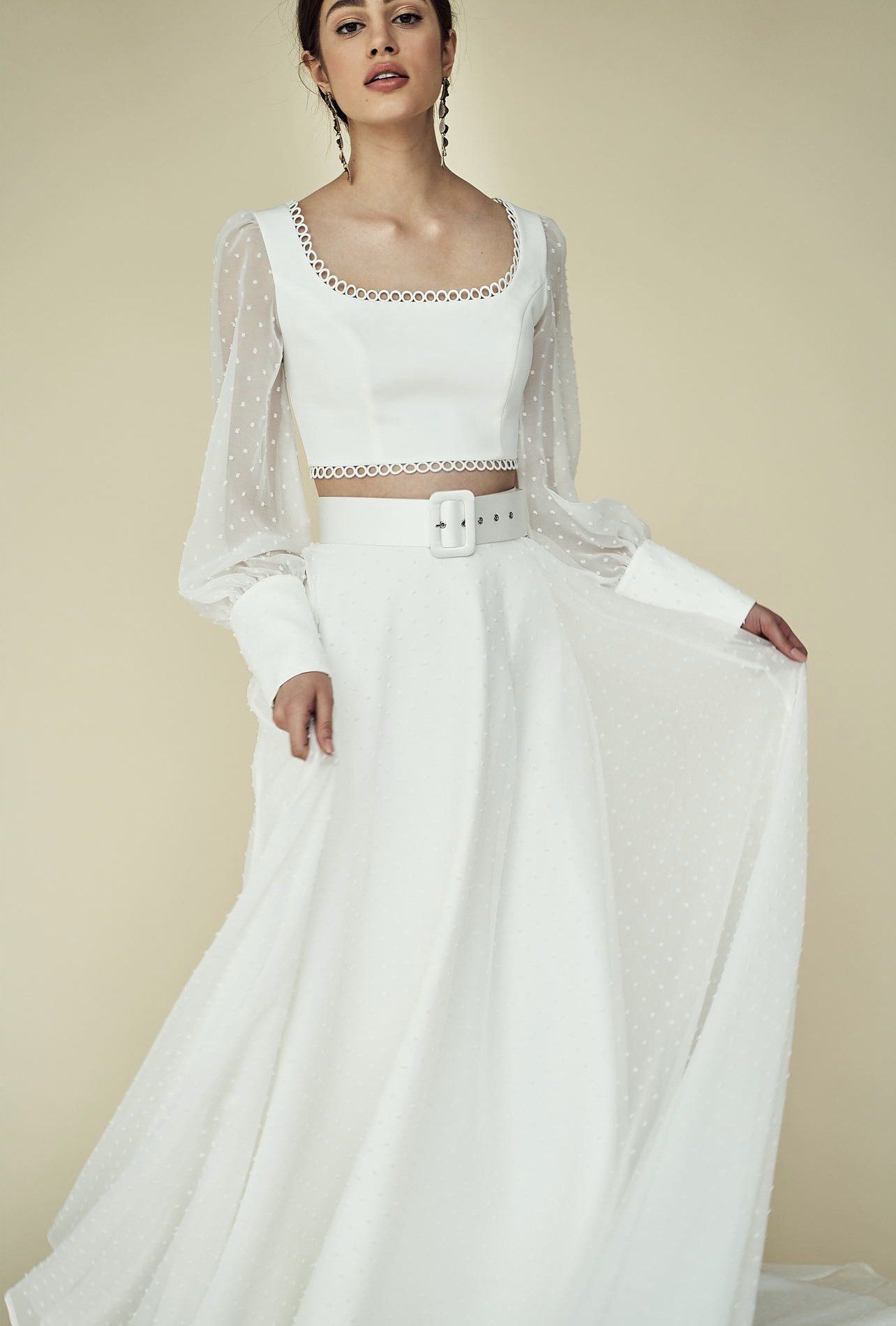 Eine Frau trägt ein weißes bauchfreies Top und einen weißen Rock.