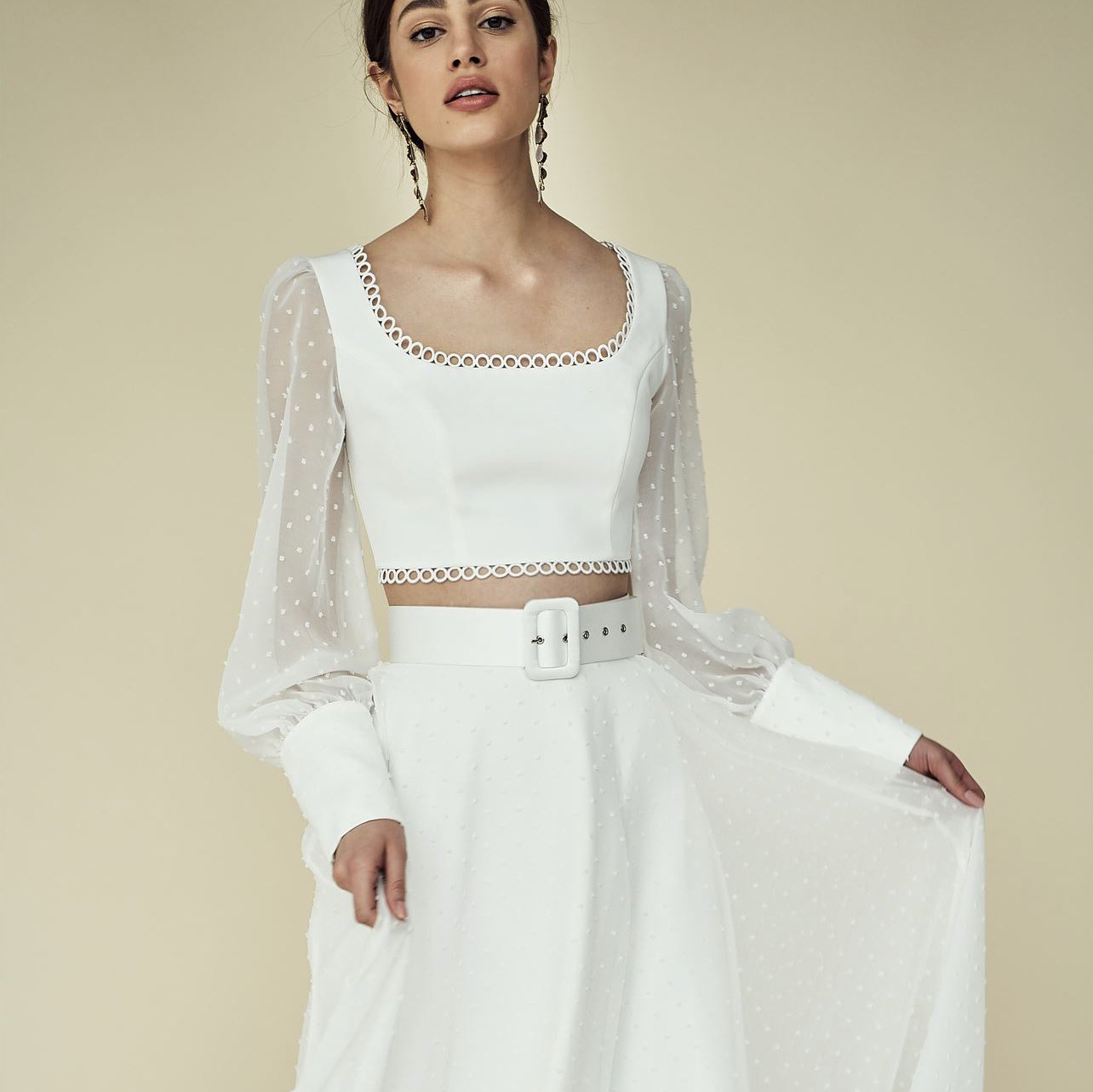 Eine Frau trägt ein weißes bauchfreies Top und einen weißen Rock.