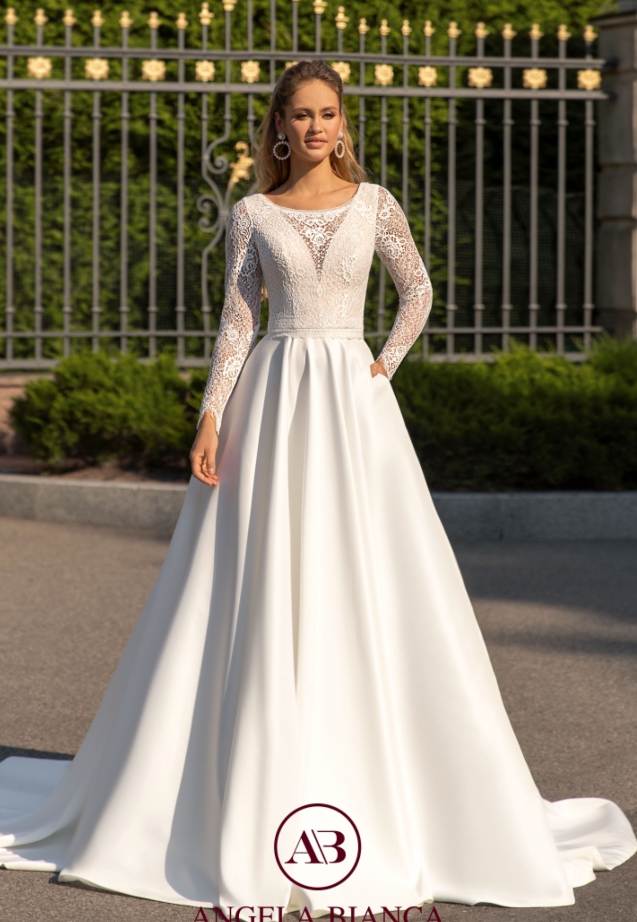 Eine Frau in einem weißen Brautkleid steht vor einem Zaun.