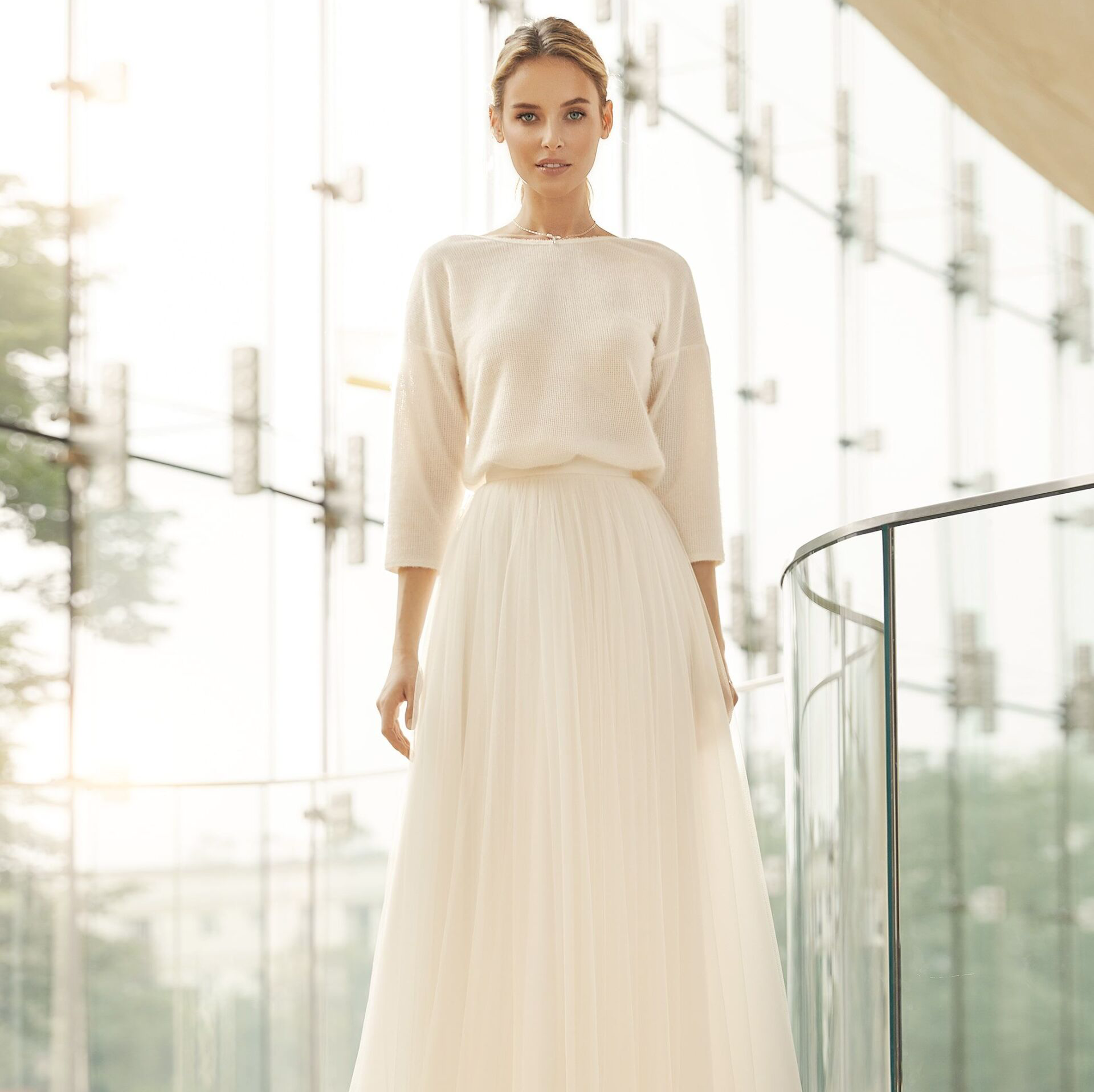 Eine Frau in einem weißen Kleid steht auf einem Balkon.