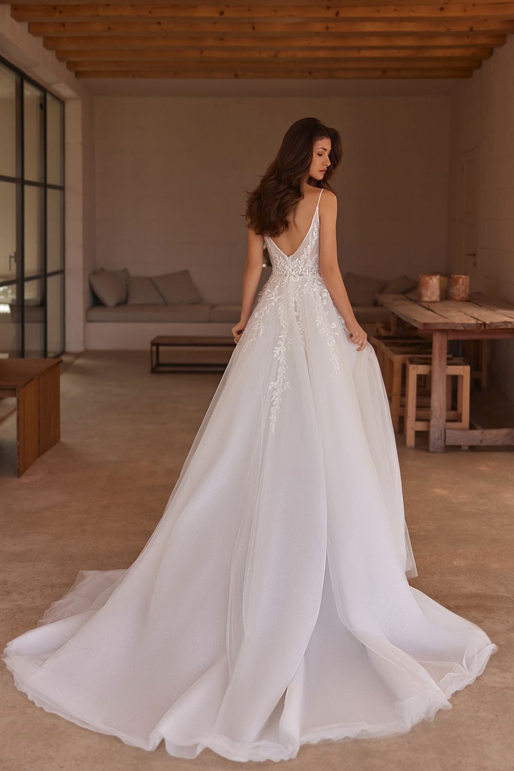 Eine Frau in einem weißen Brautkleid steht in einem Raum.