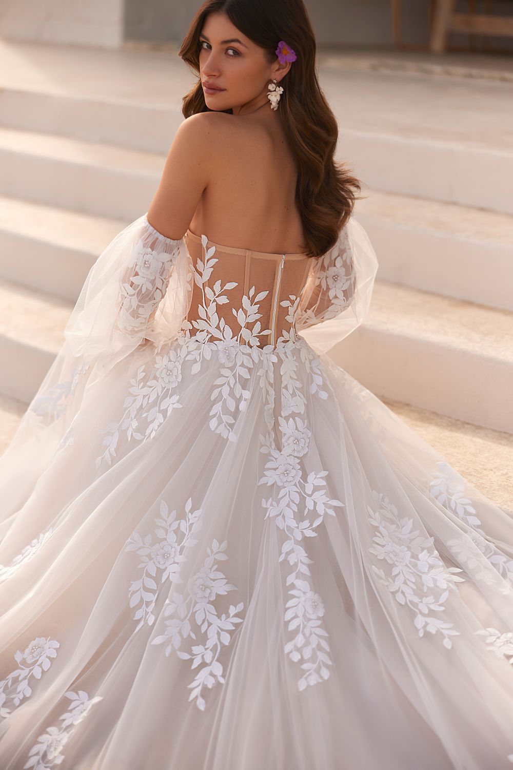 Eine Frau in einem weißen Brautkleid steht auf einer Treppe.