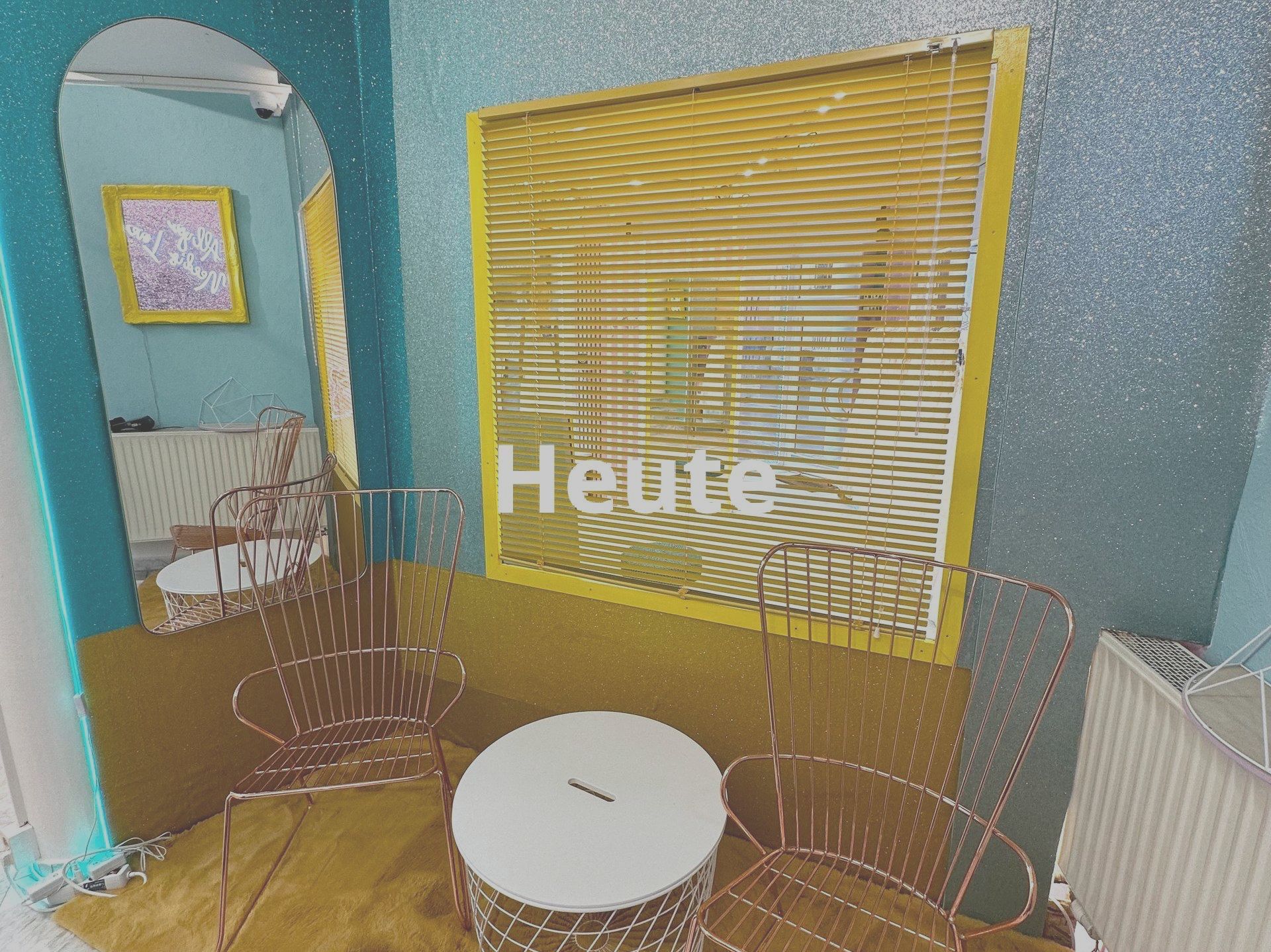 Ein Raum mit einem Tisch und Stühlen und dem Wort „heute“ an der Wand