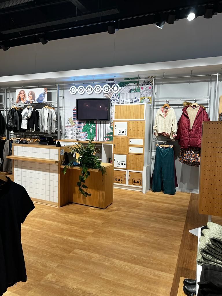 A clothing store with a wooden floor and clothes on display.