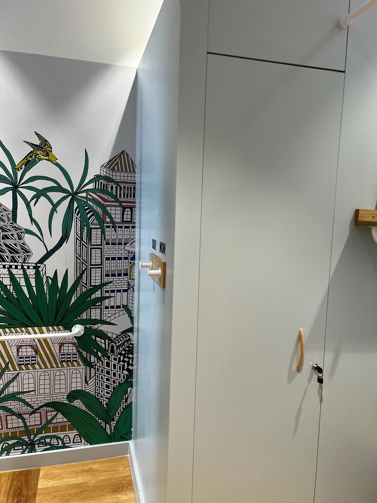 A hallway with a painting on the wall and a door.