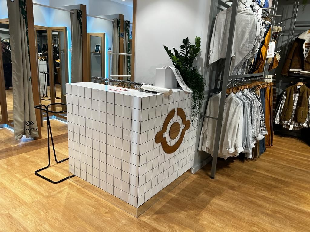 A clothing store with a white counter and clothes hanging on racks.