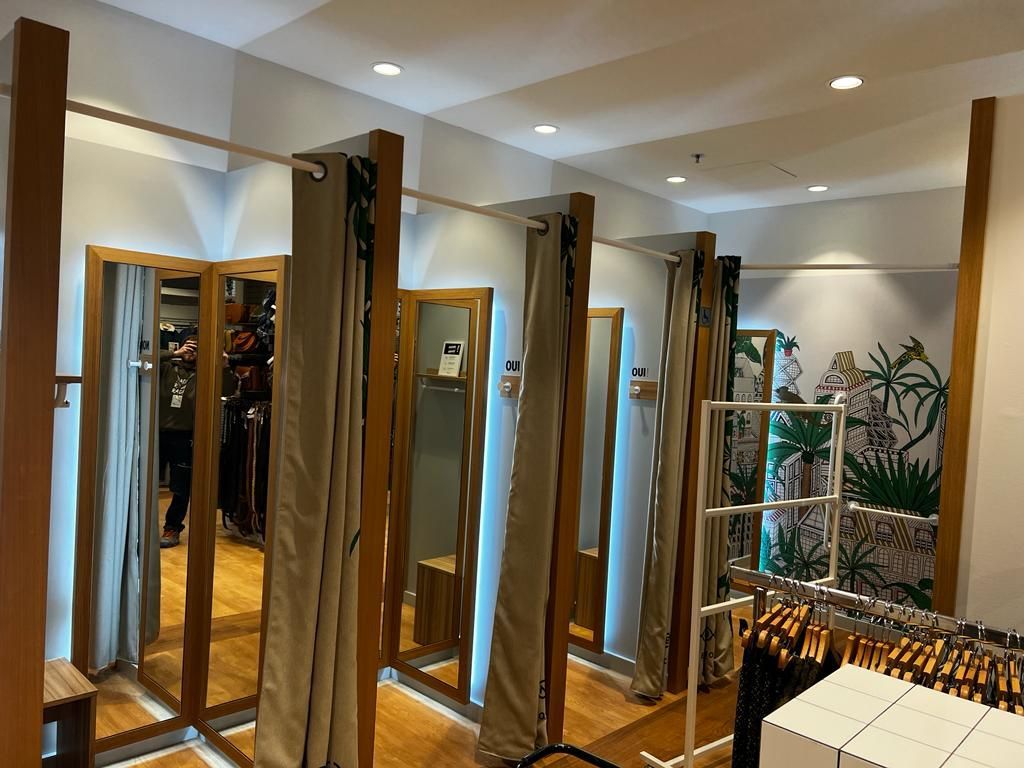 A dressing room in a store with lots of mirrors and curtains.