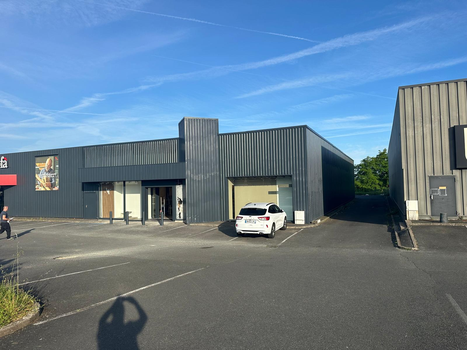 A white car is parked in front of a large building.