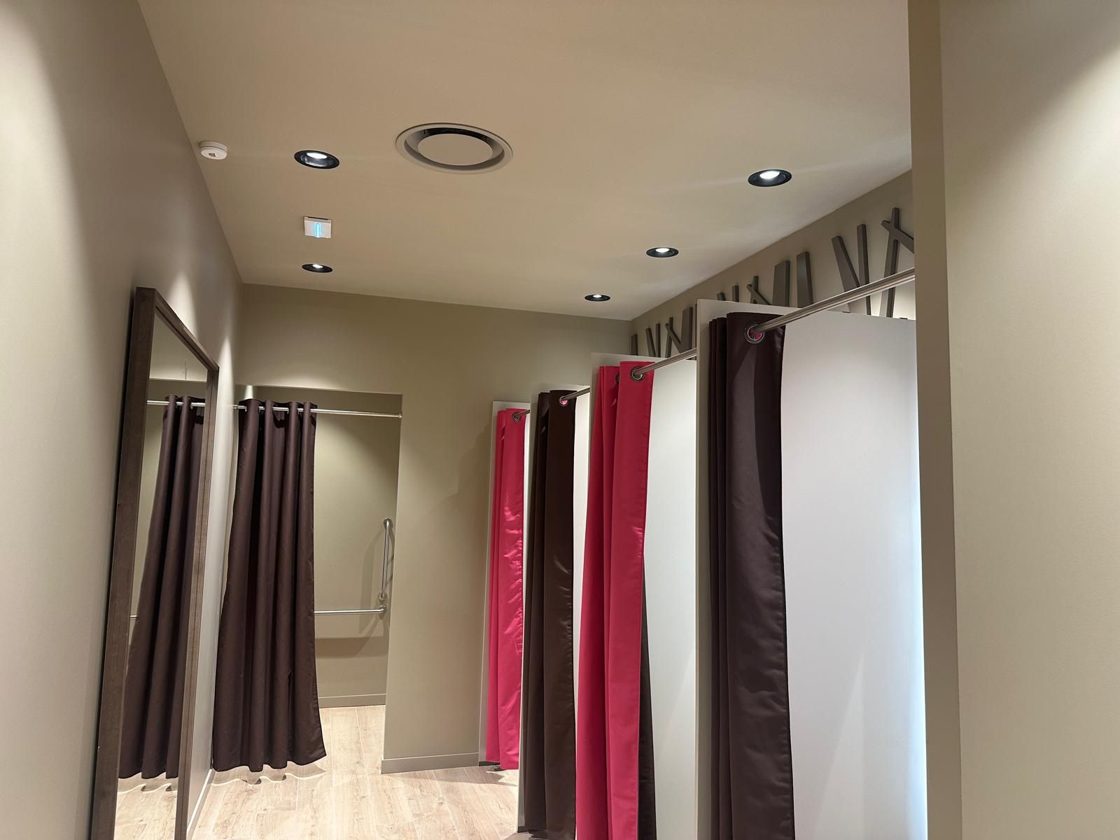A dressing room with pink and brown curtains and a mirror