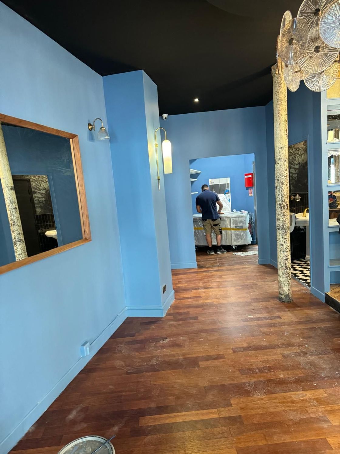 A man is standing in a room with blue walls and a wooden floor