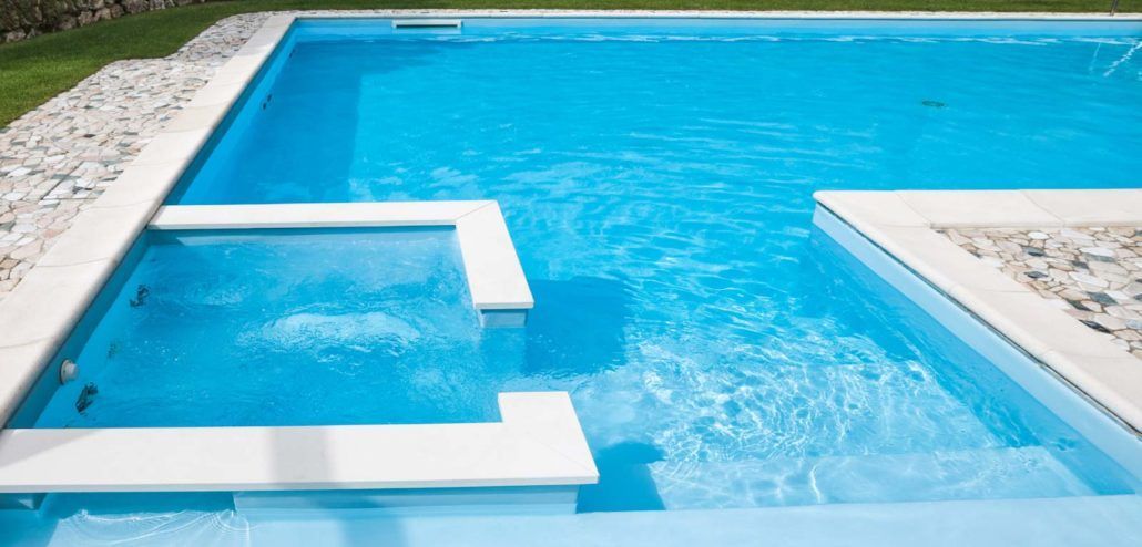 Una grande piscina piena di acqua azzurra e delle scale per accedervi.