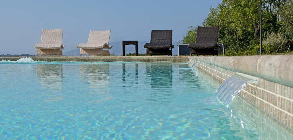 Una piscina con sedie attorno e una cascata al centro.