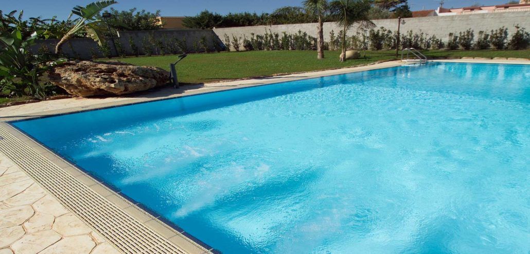 Una grande piscina piena di acqua azzurra in un cortile.