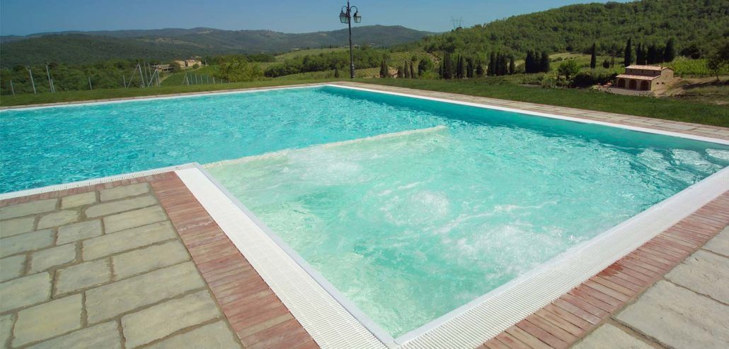 Una grande piscina con una vasca idromassaggio al centro.