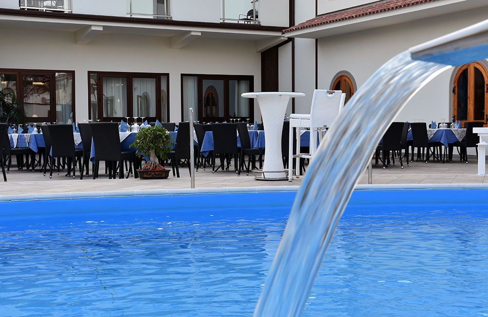 Una piscina con cascata e tavoli e sedie sullo sfondo
