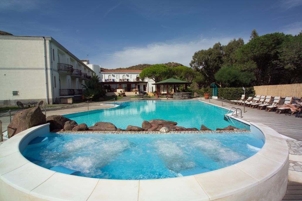 Una grande piscina con una jacuzzi al centro