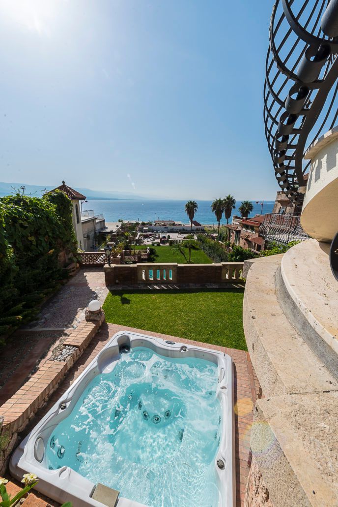 Nel cortile di una casa si trova una vasca idromassaggio con vista sull'oceano.