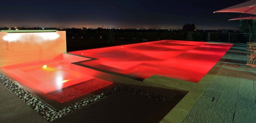 Una grande piscina è illuminata di notte con luci rosse.