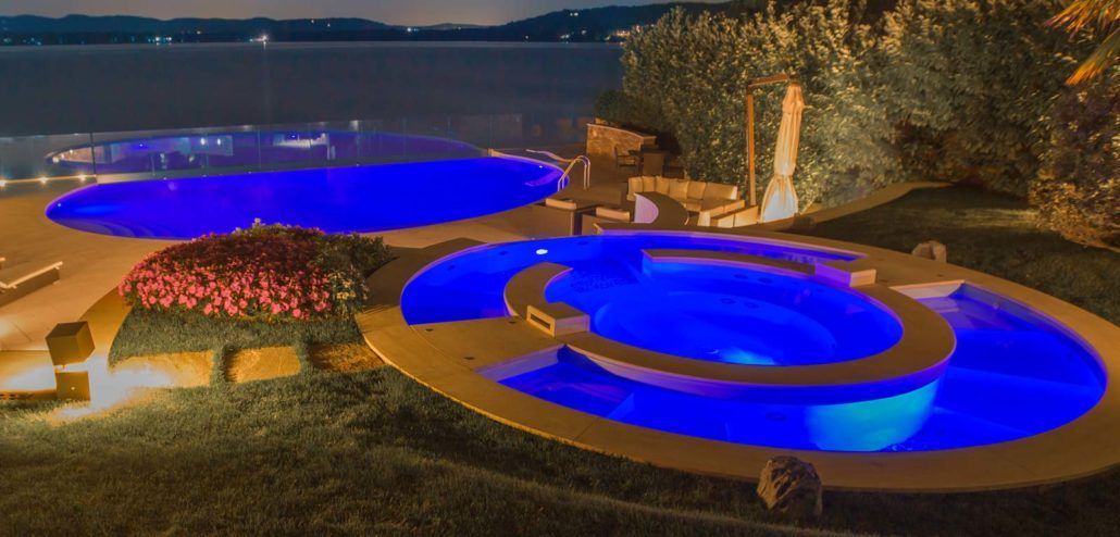 Una grande piscina è illuminata di notte con luci blu.