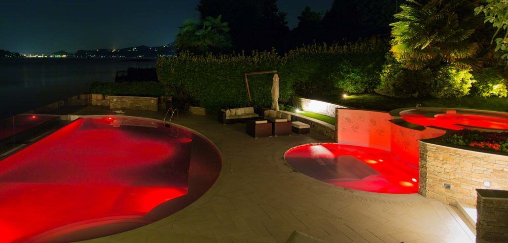 Una grande piscina è illuminata di notte con luci rosse.