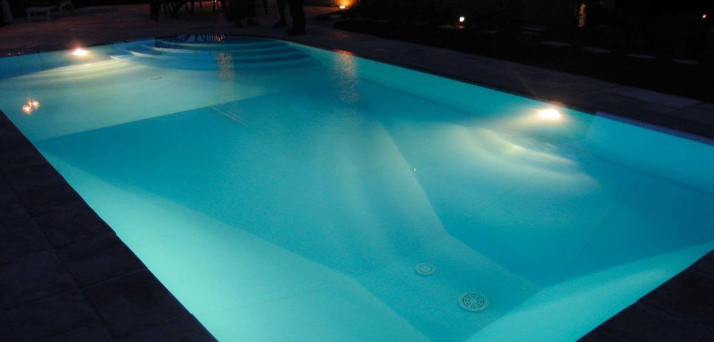 Una grande piscina è illuminata di notte.