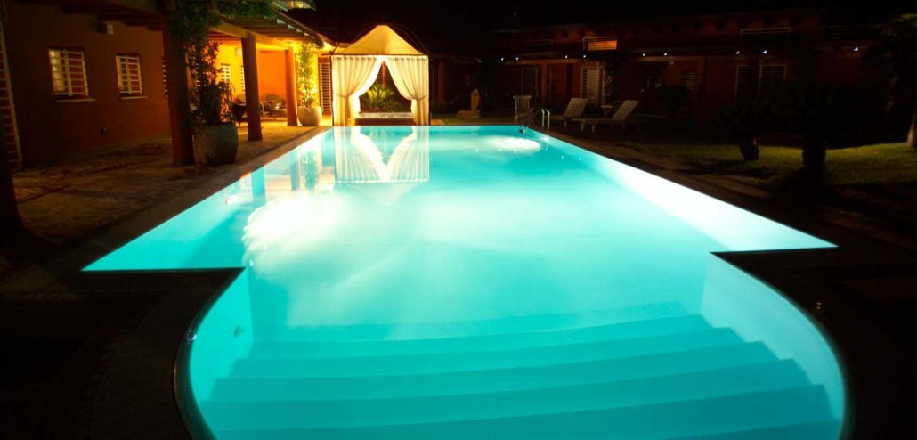 Una grande piscina è illuminata di notte.