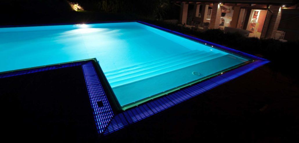 Una grande piscina è illuminata di notte.