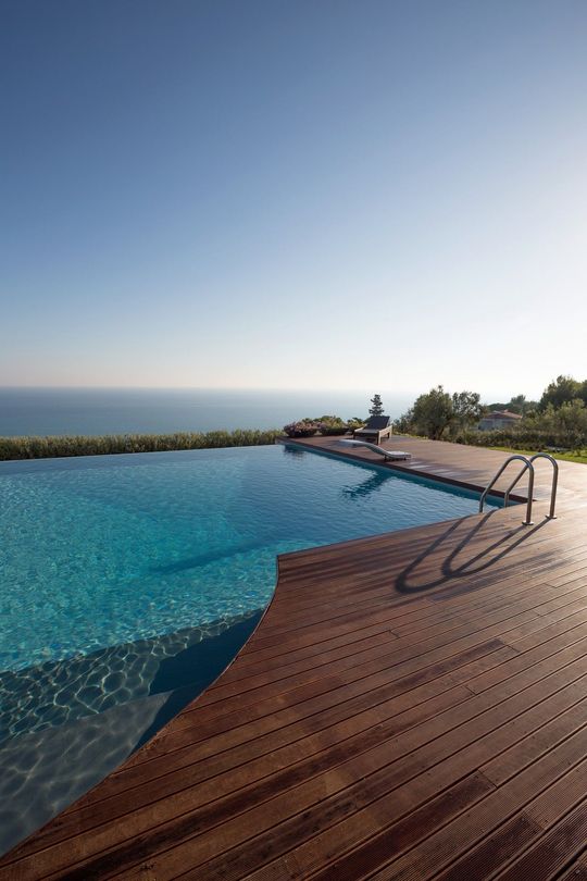 Una grande piscina circondata da un ponte in legno con vista sull'oceano