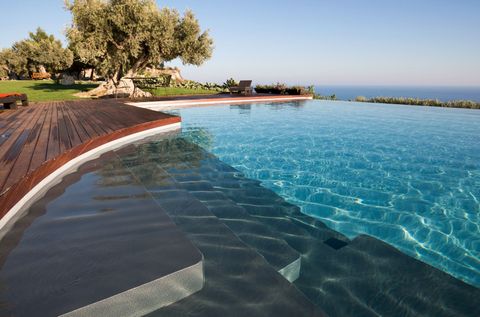 Una piscina con vista sull'oceano e un albero sullo sfondo