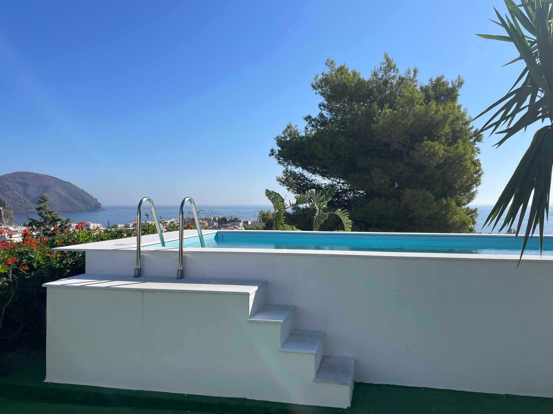 Una piscina con scale per accedervi e vista sull'oceano.