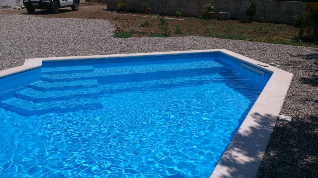 Una piscina blu con scale e un'auto parcheggiata sullo sfondo.