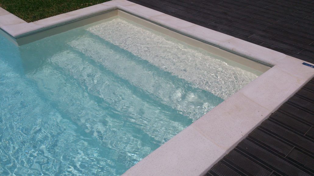 Una piscina con scale per accedervi e una terrazza in legno.