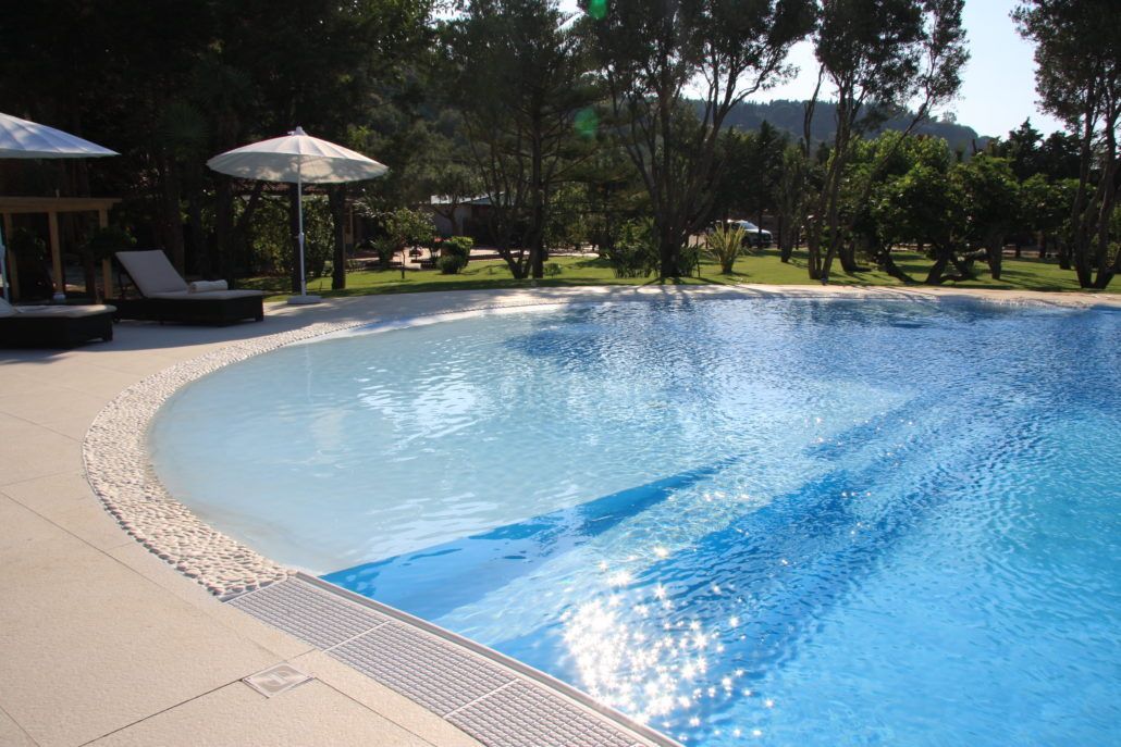 Una grande piscina con ombrelloni e sedie intorno.