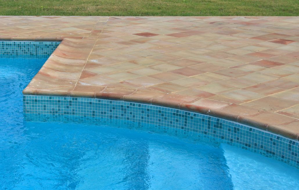 Una piscina con bordo in mattoni e gradini per accedervi.