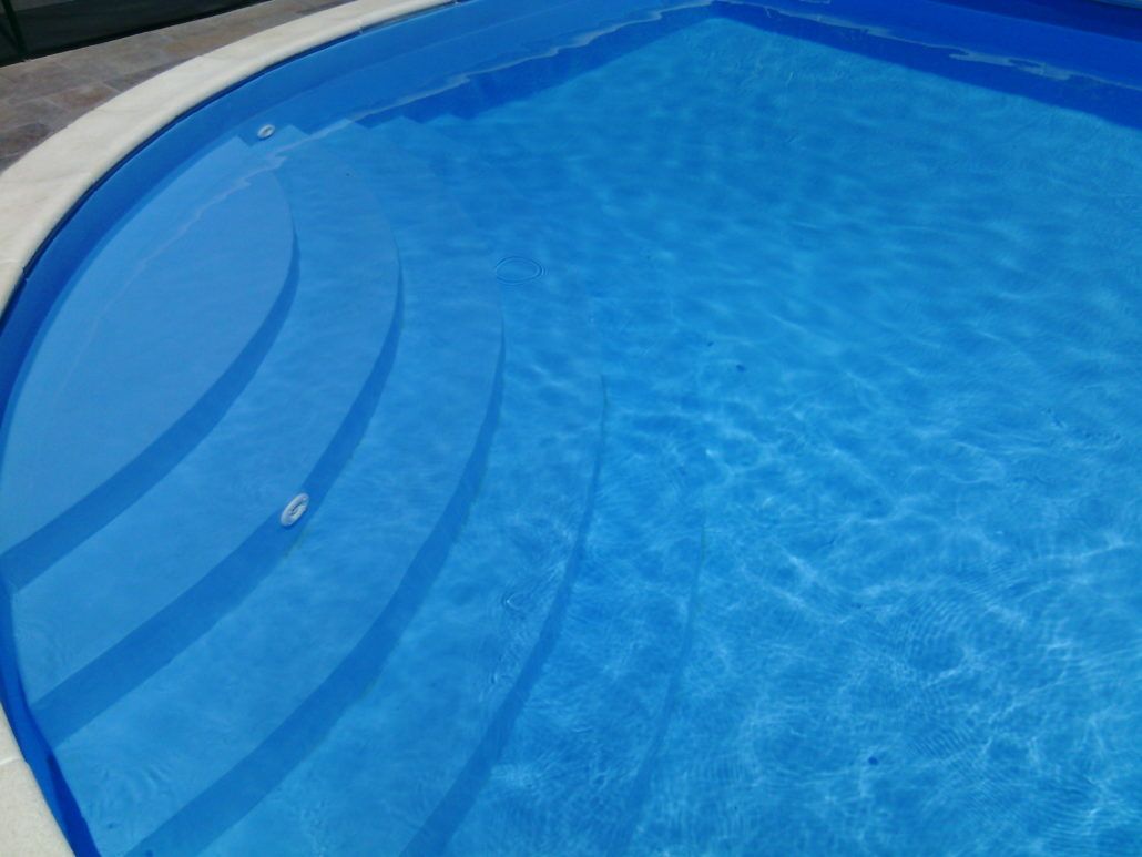 Una piscina con acqua azzurra e gradini bianchi
