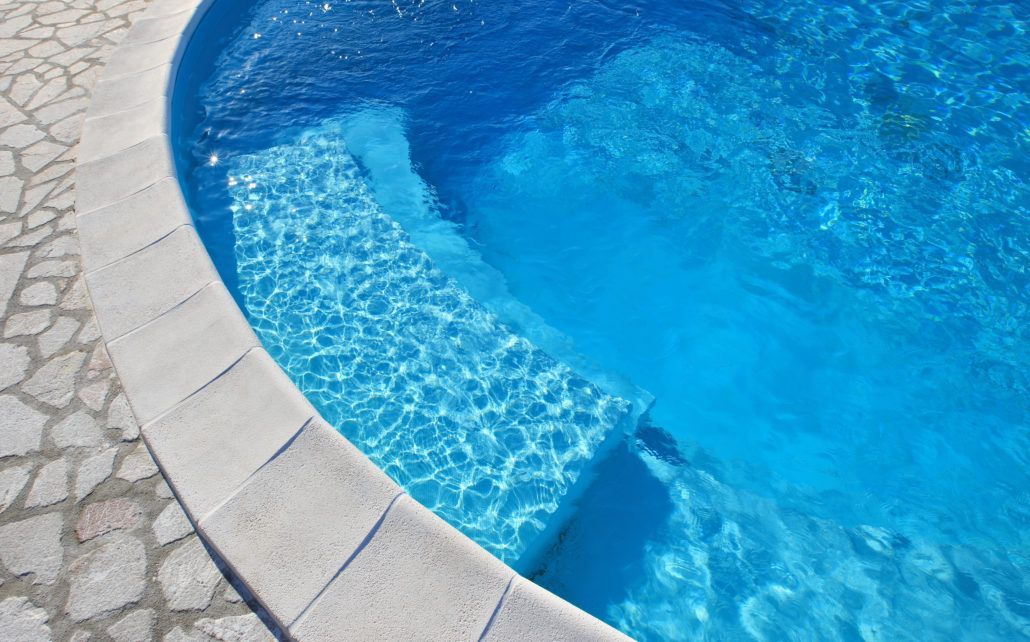 Un primo piano di una piscina con acqua azzurra e gradini.