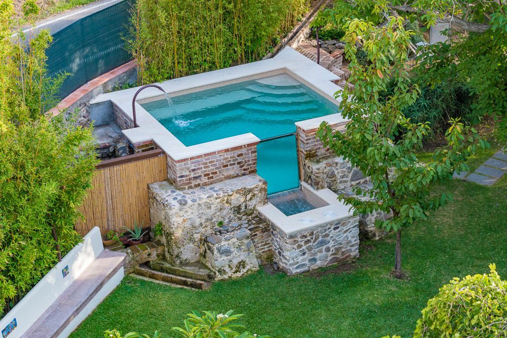 Una vista aerea di una piccola piscina in un cortile circondato da alberi.