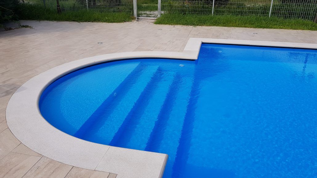 Una grande piscina blu con scale per accedervi.