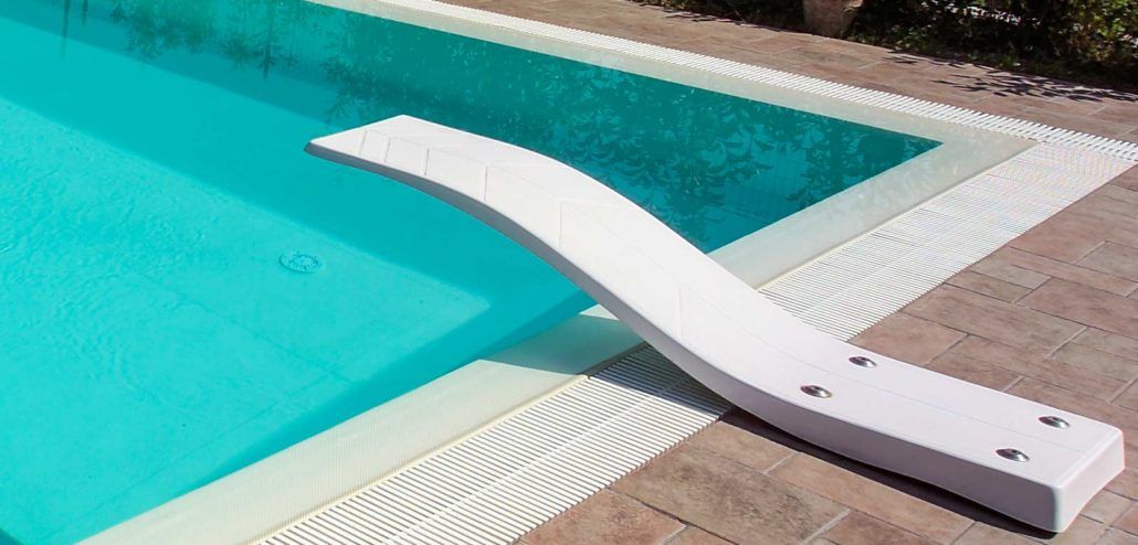 Un trampolino bianco è posizionato accanto a una piscina.