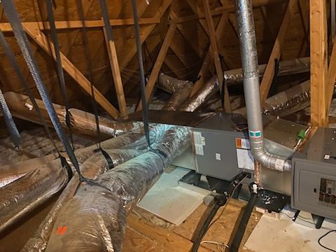 An attic with a lot of ducts hanging from the ceiling