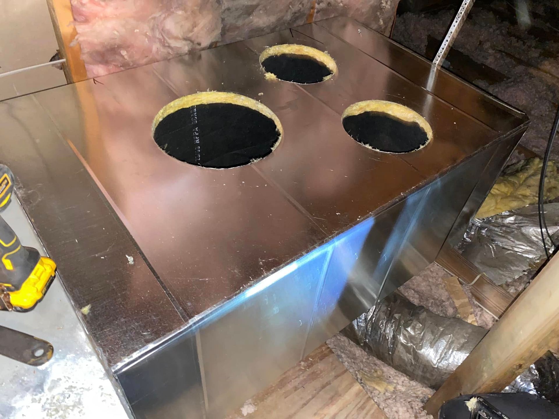 A metal box with four holes in it is in an attic.