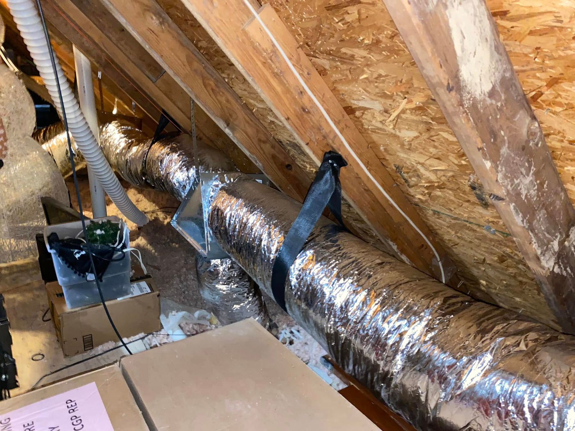 A metal pipe is hanging from the ceiling of an attic.