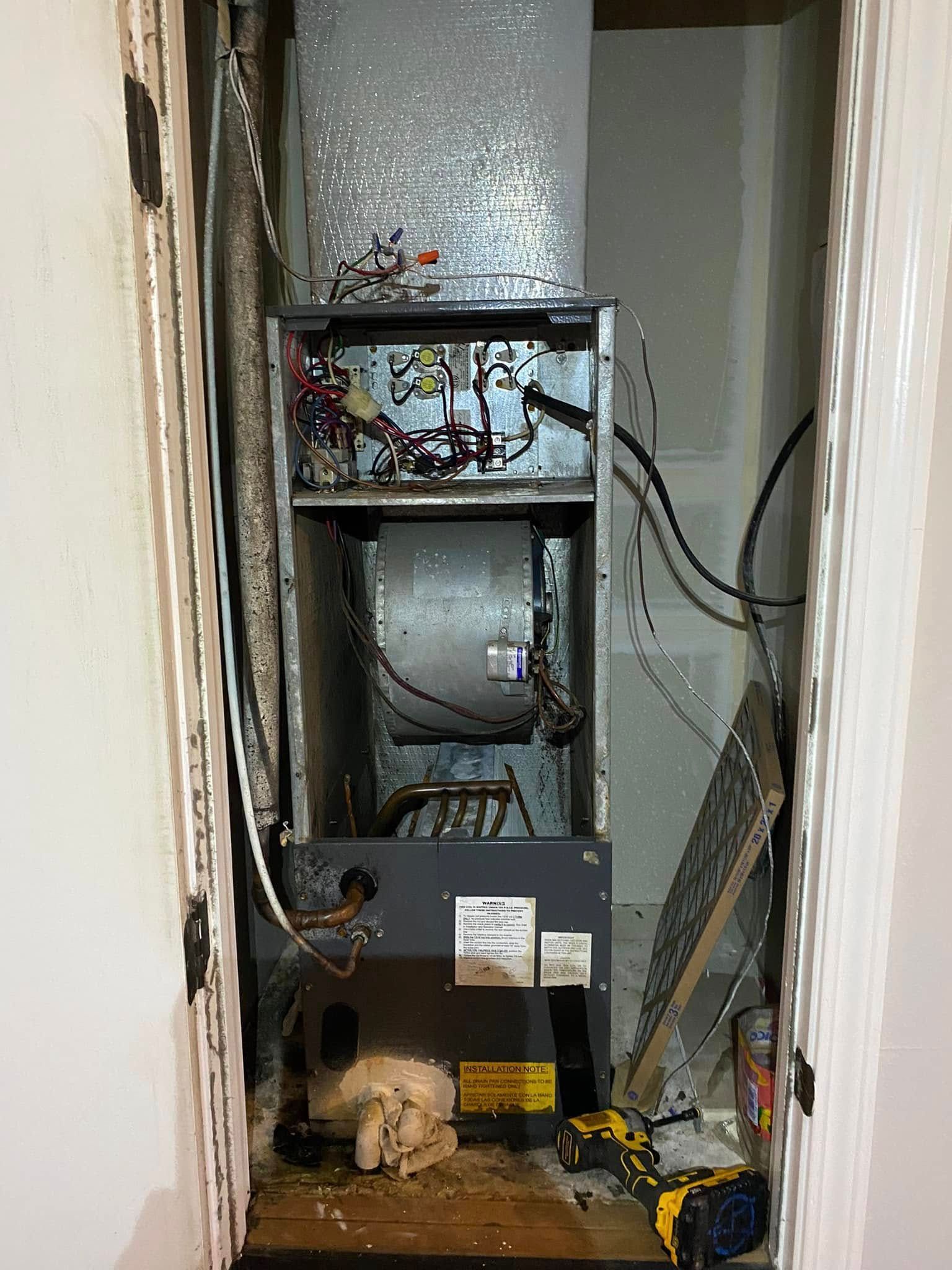 A broken air conditioner is sitting in a closet next to a door.