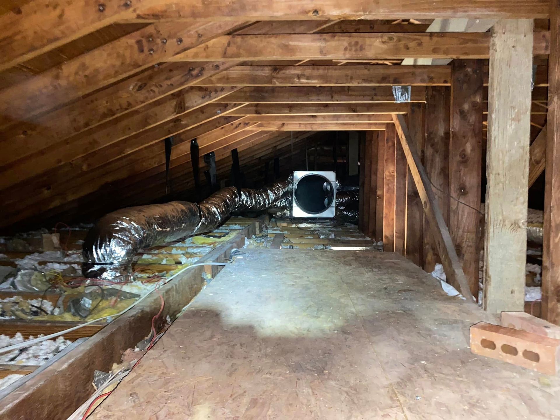 There is a fan in the attic of a house.