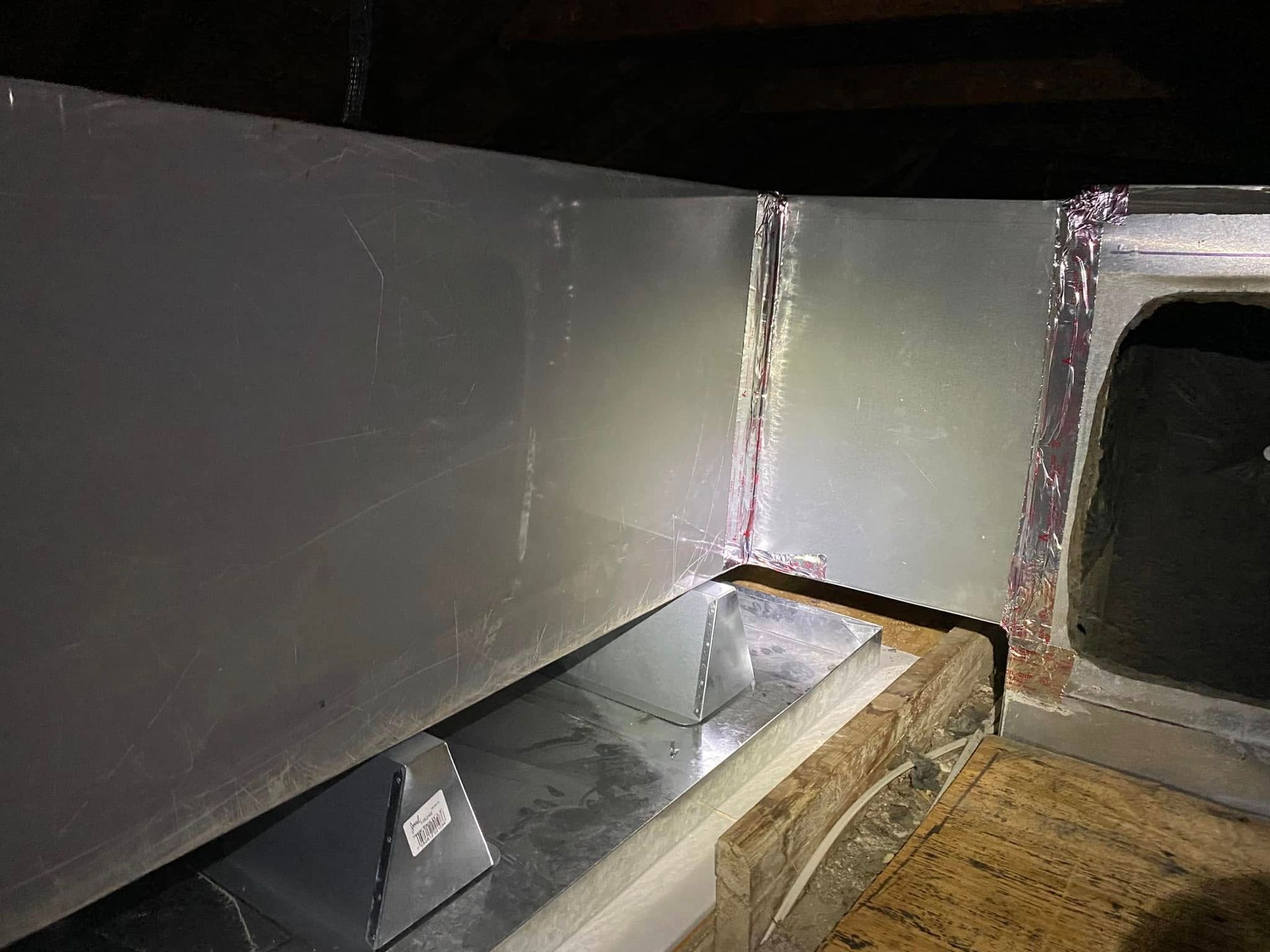 A metal pipe is sitting on top of a wooden floor in a dark room.