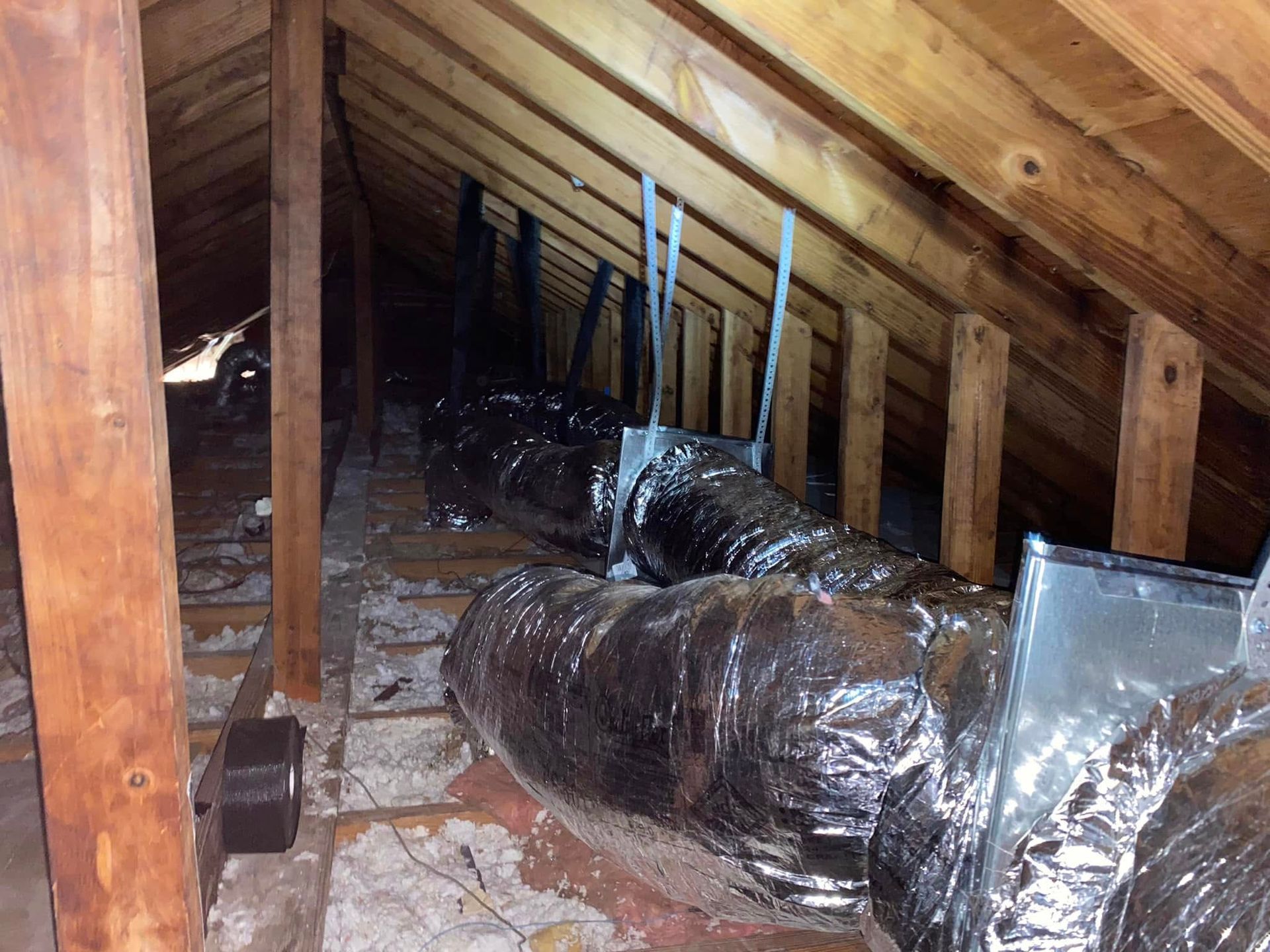 An attic with a lot of ducts hanging from the ceiling